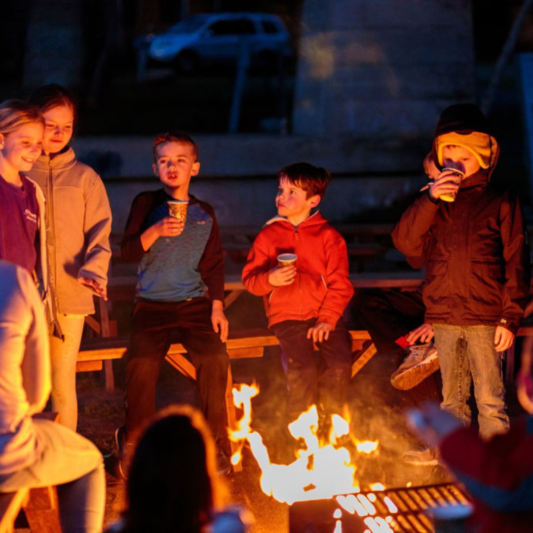 kids eating around a campfire