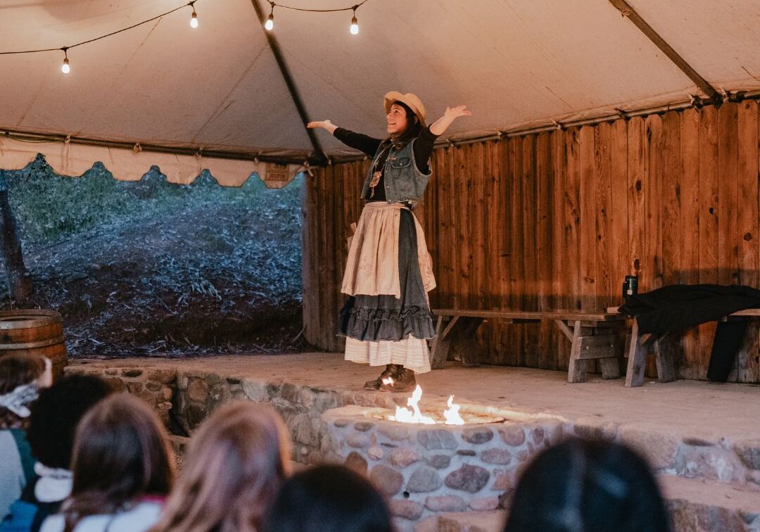woman standing on stage telling kids stories