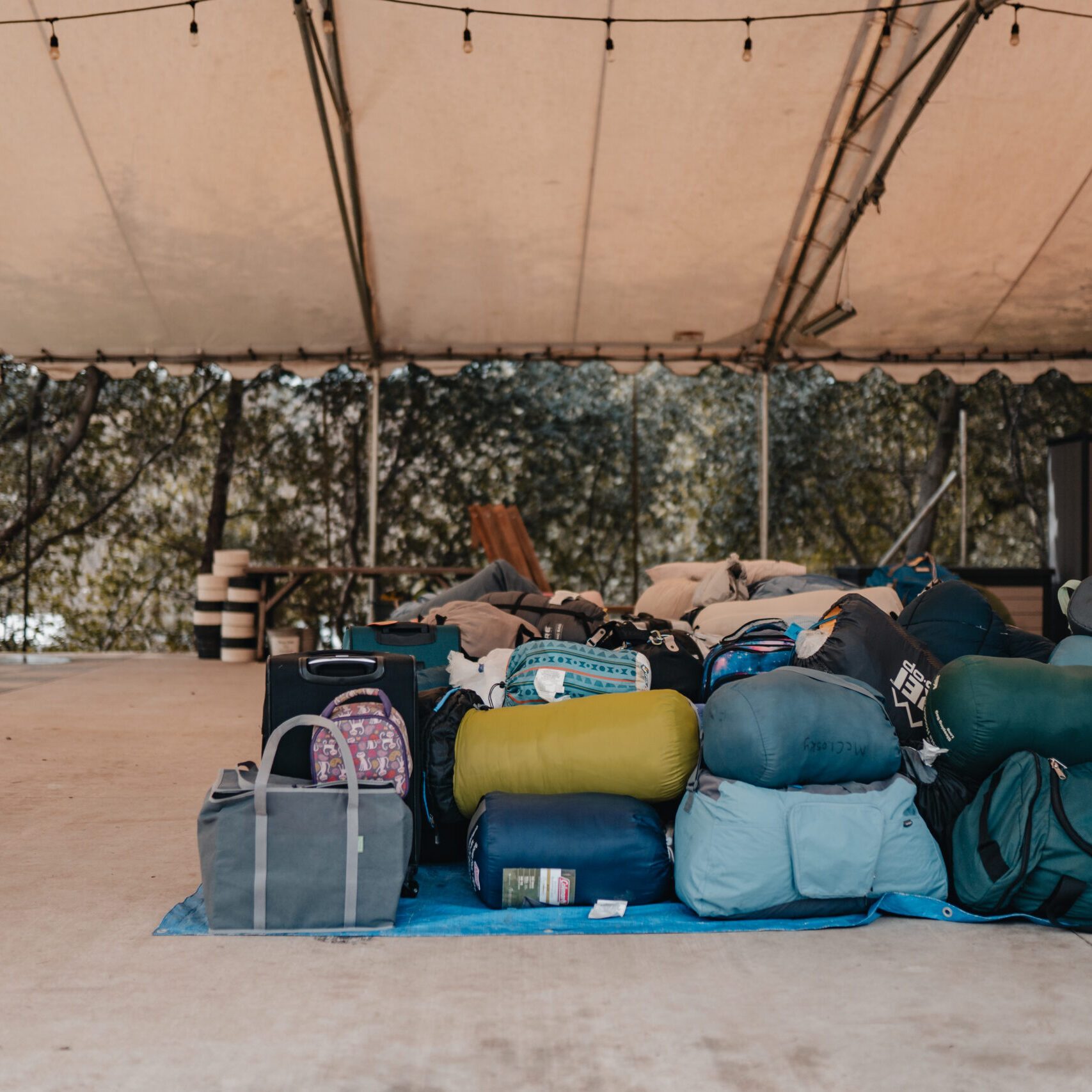 kids' backpacks piled on top of each other under tent